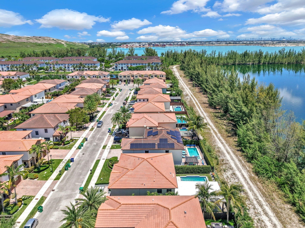 Drone view over a Doral residential community with palm-lined streets, homes, pools and a lake